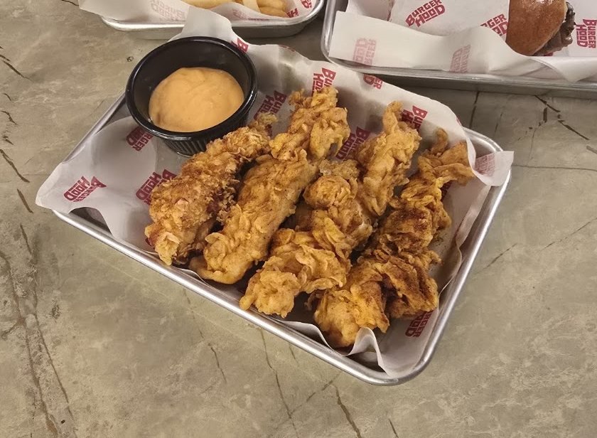 Crispy chicken tenders with dipping sauce on a Burgerhood tray